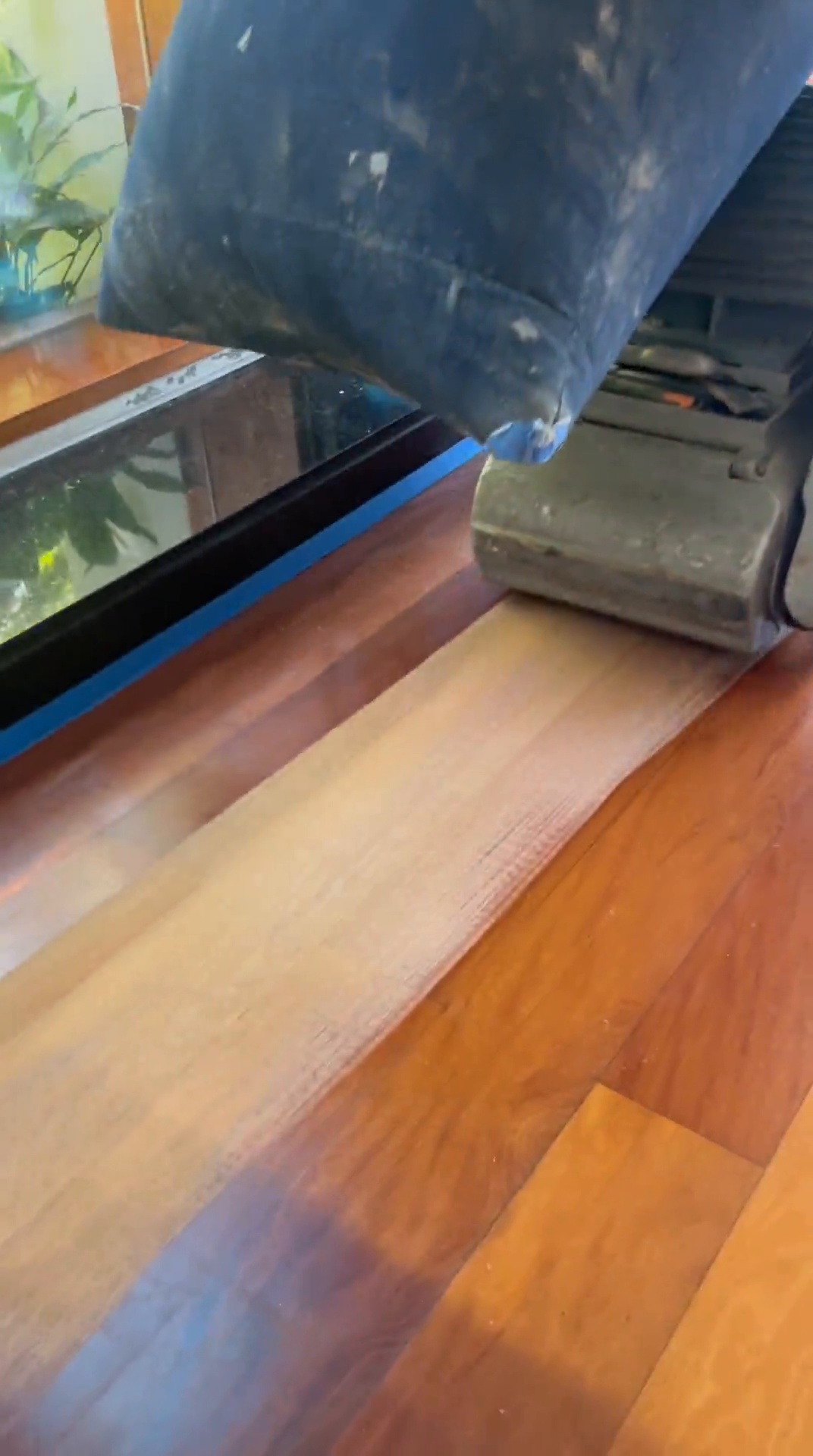 Lijadora puliendo un piso de madera, mostrando el contraste entre lo oscuro y lo recién restaurado